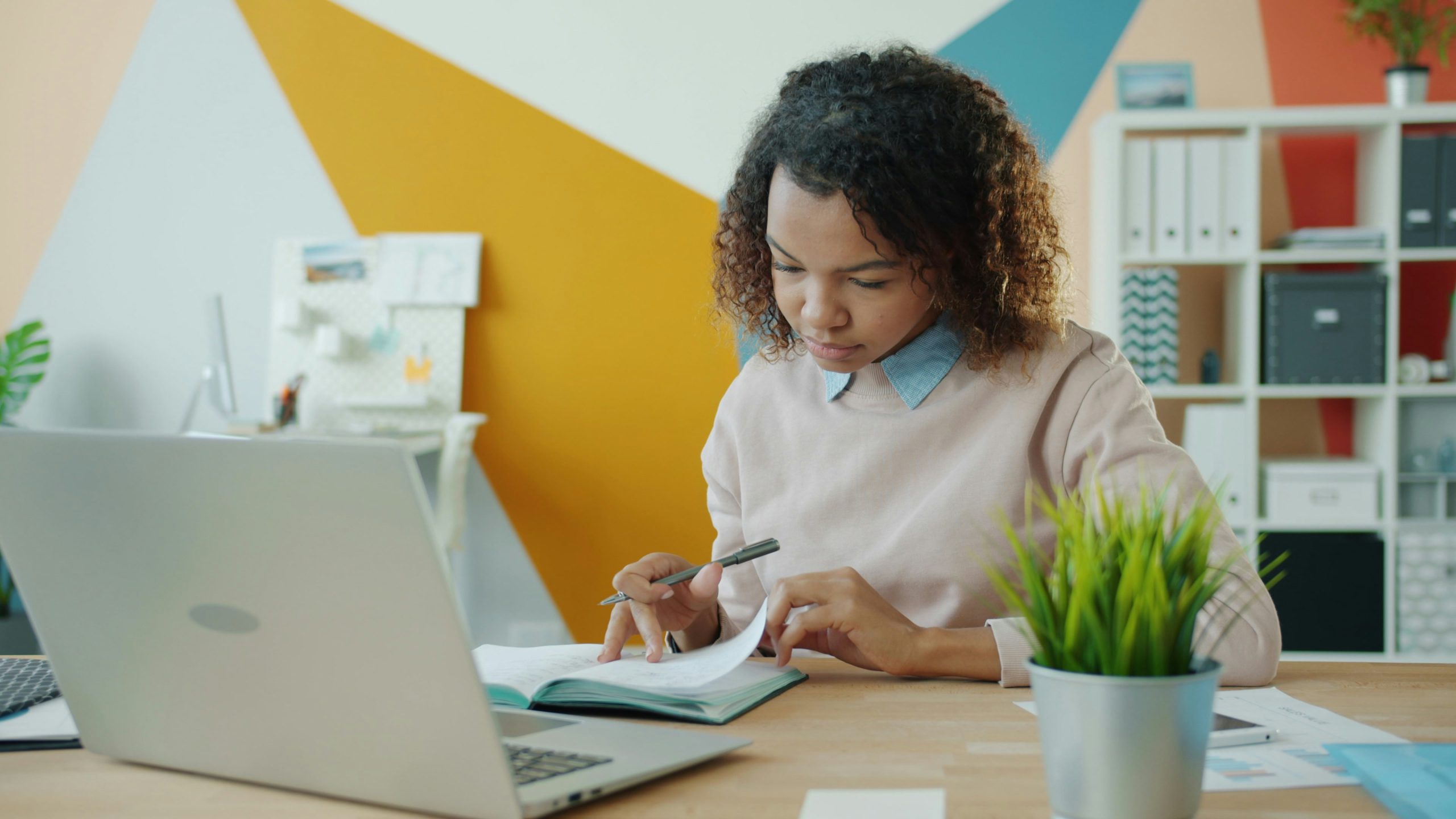 Woman working at a desk with a laptop and a notebook